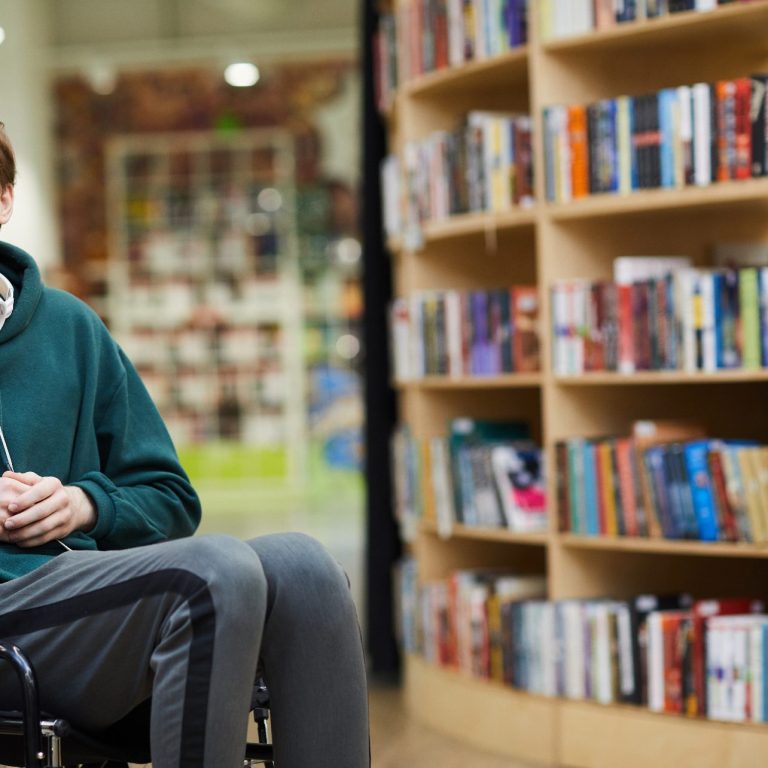 content handsome, iStock-1141509310 von SeventyFour, Lizenz erworben am 28.01.2026 Sitzende Person in einer Bibliothek